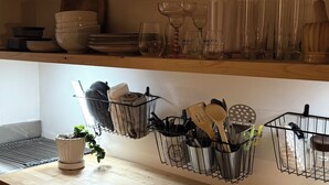 A kitchen with wooden countertops, hanging utensil racks, and a variety of glassware and plates.