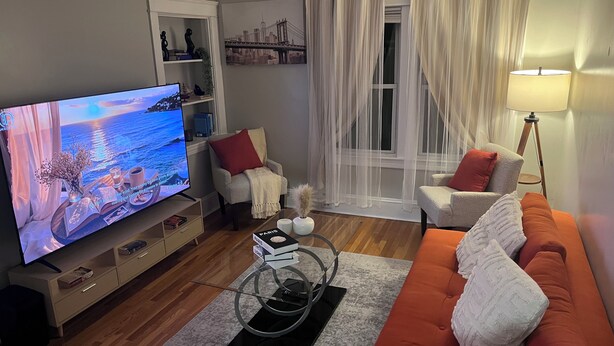 A living room with a TV, two armchairs, a sofa, a coffee table, and a lamp. - Spacious 5-bedroom apartment (Worcester)