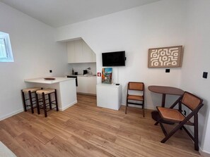 Eine moderne Küche mit weißen Schränken, einer zentralen Kochinsel und einem Essbereich mit Tisch und Stühlen.