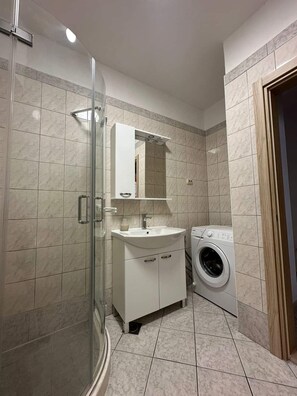 A bathroom with a glass shower enclosure, a sink with a mirror above it, and a washing machine. - 2-bedroom apartment in fabulous Sevid na moru with AC (Sevid na moru)