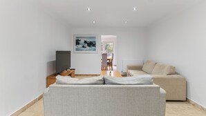 A modern living room with a sofa, a TV, a dining area with chairs, and a painting on the wall. - Modern 5 Bed Fully Detached Guest House (with parking) (Walsall)