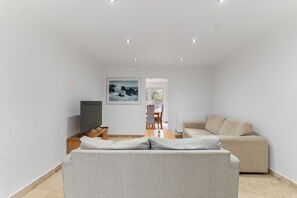 A modern living room with a sofa, a TV, a dining area with chairs, and a painting on the wall. - Modern 5 Bed Fully Detached Guest House (with parking) (Walsall)