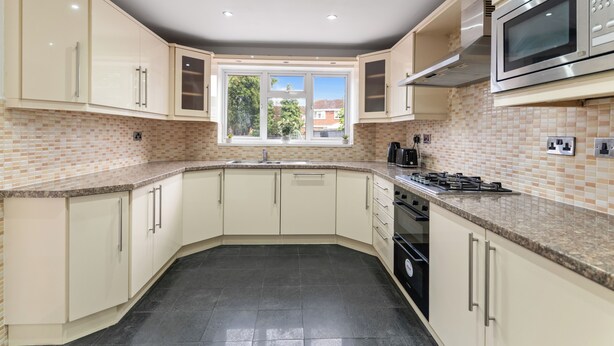 A kitchen with a window, cabinets, a stove, and a microwave. - Modern 5 Bed Fully Detached Guest House (with parking) (Walsall)