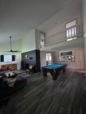 A spacious living area with a pool table, a ceiling fan, and a TV. - Spacious 5-bedroom 2 bath newly renovated house in beautiful Seabrook, new AC. (Seabrook)