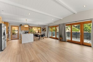 Une cuisine spacieuse dotée d’un îlot central, de meubles en bois et d’une grande porte-fenêtre coulissante donnant sur un balcon.