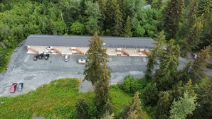Une vue aérienne d’un bâtiment doté de nombreux espaces de stationnement, entouré d’une forêt dense.