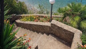 Une vue sur la côte, avec un ciel dégagé, une côte rocheuse et un escalier en pierre menant à la plage.