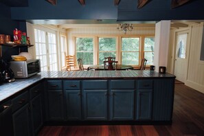 A kitchen with a central island, wooden cabinets, and a dining area with chairs.