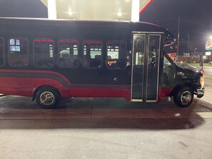 Ein schwarz-roter Bus ist an einer Tankstelle geparkt, im Hintergrund ist ein Burger King Schild zu sehen.
