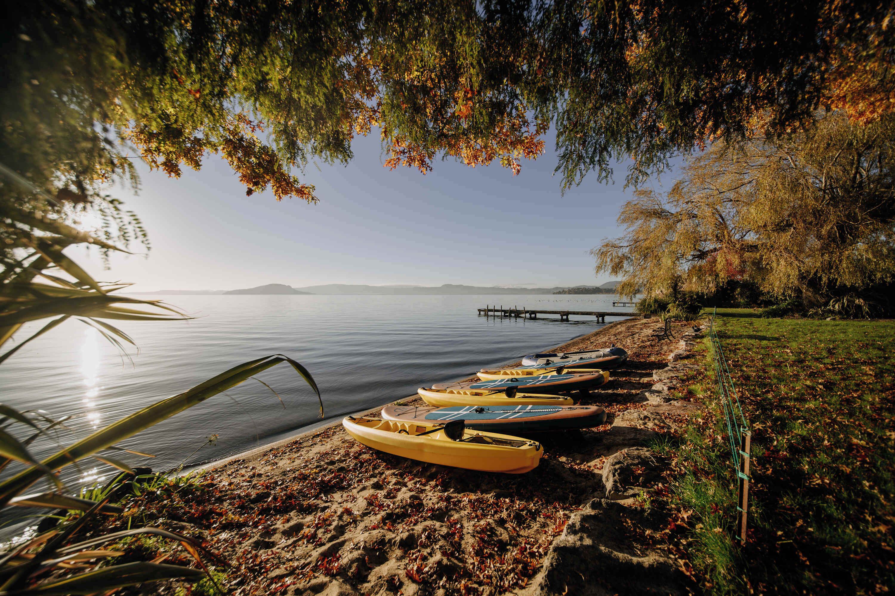 Kayak aparcats a la riba sorrenca d'un llac tranquil, amb un moll al fons.