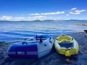 Two inflatables on a sandy beach with a calm sea and distant mountains.