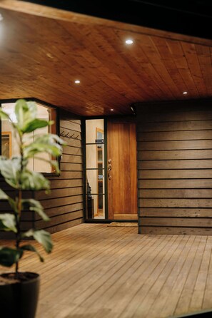A wooden interior with a wooden door, a potted plant, and a wooden floor.