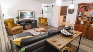 Uma sala de estar moderna com sofá, poltronas, lareira, mesa de centro e estante de livros.