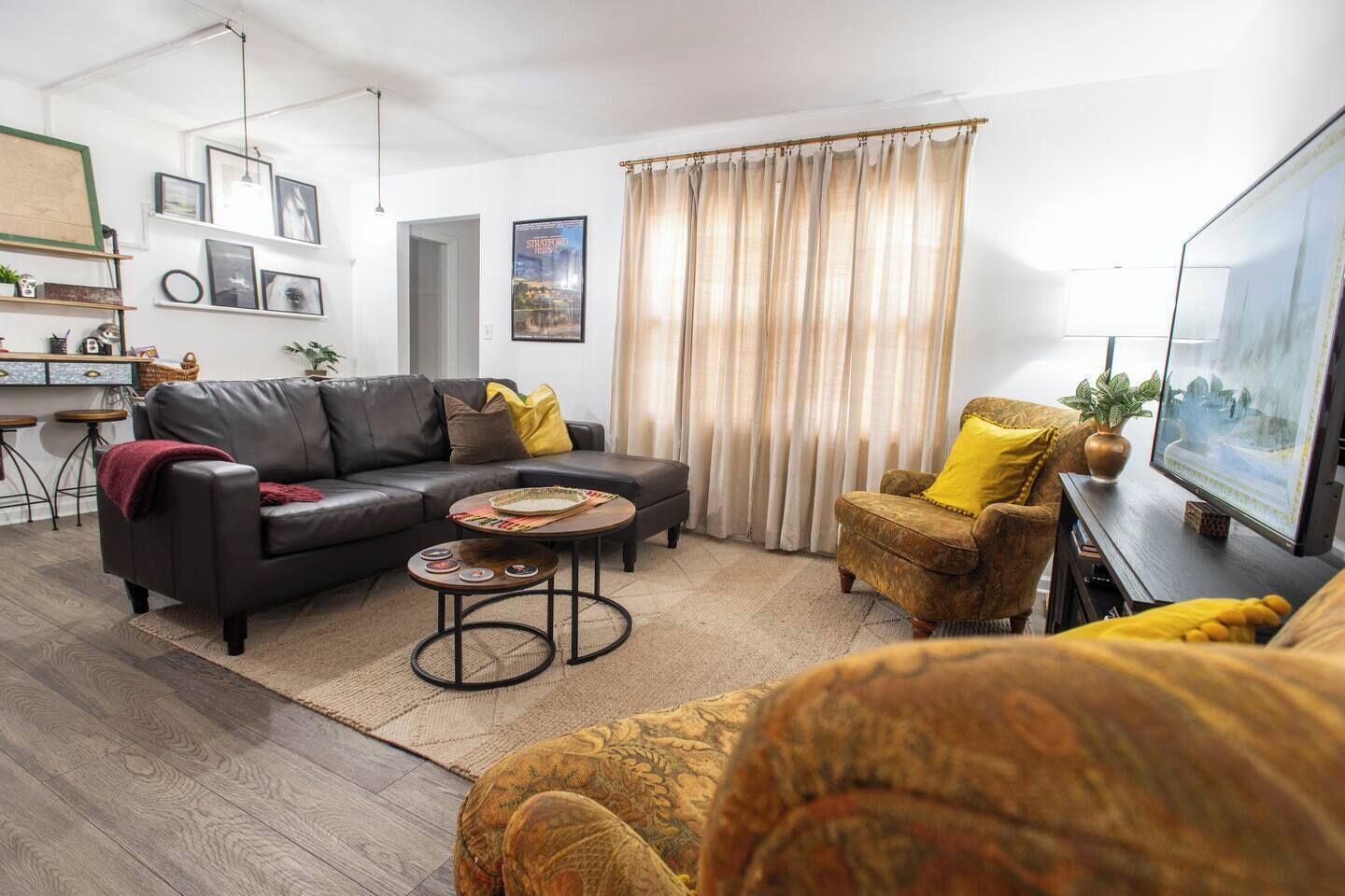 Ein Wohnzimmer mit Sofa, Sessel, Couchtisch und Fernseher.