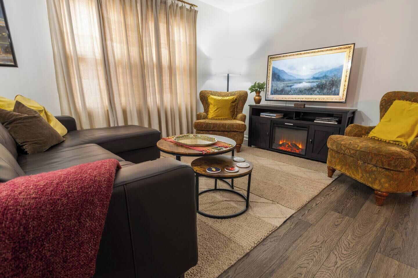 Ein Wohnzimmer mit einer Couch, Sesseln, einem Couchtisch, einem Kamin und einem Fernseher.