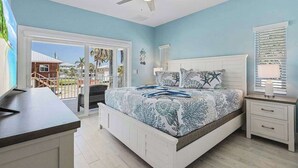 A bedroom with a bed, a ceiling fan, a nightstand, and a view through a sliding glass door. - Beach Time  - Elevator - Pool - 3 Min to Beach (Fort Myers Beach)