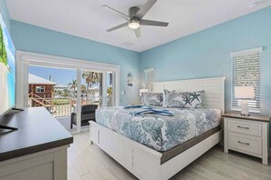 A bedroom with a bed, a ceiling fan, a nightstand, and a view through a sliding glass door. - Beach Time  - Elevator - Pool - 3 Min to Beach (Fort Myers Beach)