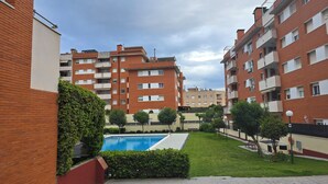 Un edificio residencial con piscina, rodeado de vegetación y otros edificios de apartamentos.
