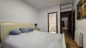 Un dormitorio con cama, mesita de noche, lámpara y espejo.