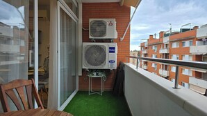 Un balcón con un aire acondicionado Mitsubishi Electric, un inverter Haier y una planta pequeña.