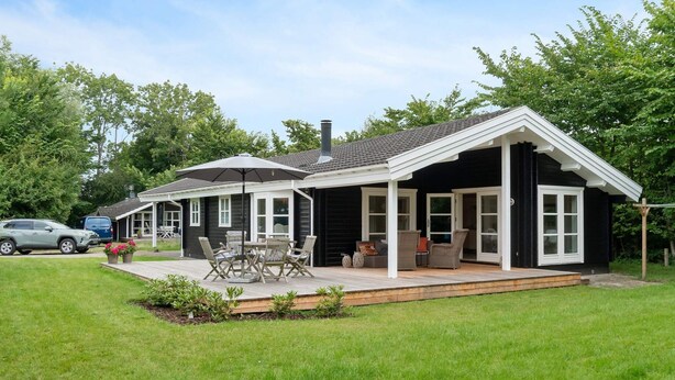 A house with a covered patio, a car parked in the driveway, and a lawn. - 5 Star Holiday Home in Faxe Ladeplads (Faxe Ladeplads)