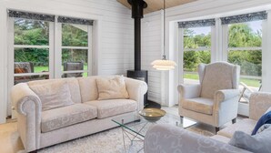 A cozy room with a sofa, armchair, and a fireplace. - 5 Star Holiday Home in Faxe Ladeplads (Faxe Ladeplads)