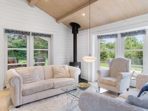A cozy room with a sofa, armchair, and a fireplace. - 5 Star Holiday Home in Faxe Ladeplads (Faxe Ladeplads)