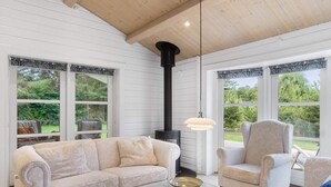 A cozy room with a sofa, armchair, and a fireplace. - 5 Star Holiday Home in Faxe Ladeplads (Faxe Ladeplads)