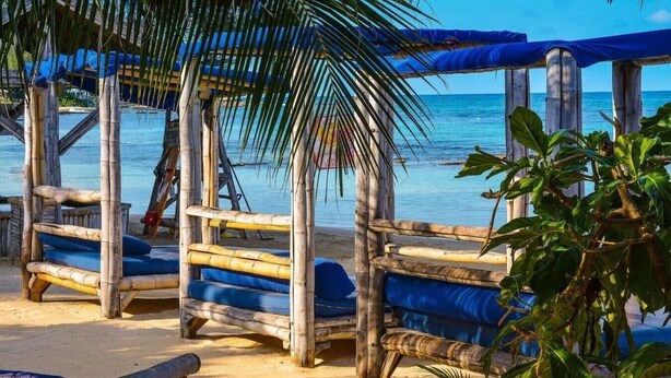 Une plage avec des structures en bois et des coussins bleus.