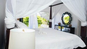 Une chambre à coucher avec un lit à baldaquin, une table de chevet avec une lampe, une commode et un miroir.