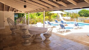 Un espace extérieur abrité comprenant une piscine, des chaises longues et une table avec des chaises.