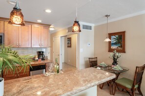 A kitchen with granite countertops, wooden cabinets, and pendant lighting. - Direct Oceanfront Studio with Lanai & Sunset Views -Lahaina Shores 331 (Lahaina)