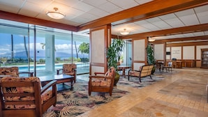 Um hall amplo com vista para a piscina, mobiliário de madeira e um tapete com tema tropical.