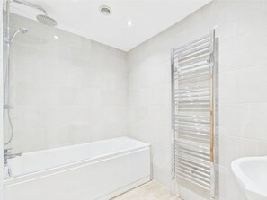 Un baño moderno con cabina de ducha de vidrio, una bañera independiente y un cabezal de ducha de cristal.