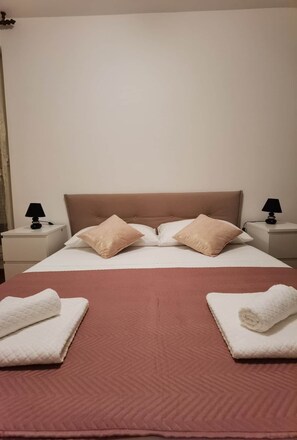Ein ordentlich bezogenes Bett mit einem braunen Kopfteil, zwei weißen Kissen und zwei gefalteten weißen Handtüchern.