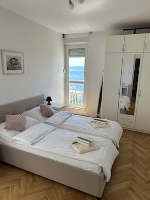 Ein Schlafzimmer mit Bett, Kleiderschrank, Fenster mit Blick und einem Bild an der Wand.