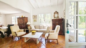 Een woonkamer met een houten salontafel, gestreept fauteuils, een bank en een kast.
