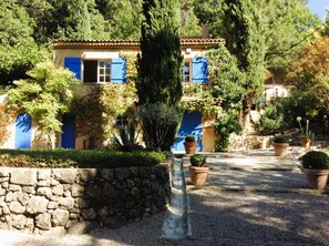 A stone wall, a building with blue shutters, and potted plants. - Charming Provençal villa with a pool and sauna (MONTFERRAT)