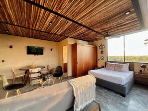 Ein Zimmer mit einem Bett, einem Schreibtisch, einem Sessel, einem Fernseher und einem großen Fenster.