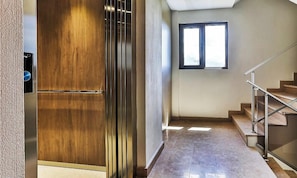 Ein Flur mit Holztür, Fenster und Treppe.