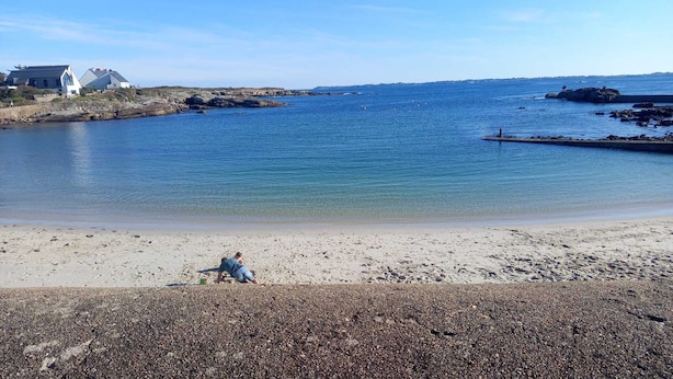 A beach with pebbles, a person sitting, and houses in the background. - Quiet house just 5 minutes from the beaches with direct access to the bike path  (Clohars-Carnoët)