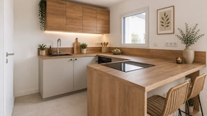 A modern kitchen with wooden cabinets, a built-in island, a window, and a potted plant. - Quiet house just 5 minutes from the beaches with direct access to the bike path  (Clohars-Carnoët)