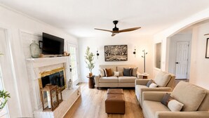 A living room with a fireplace, a television, a ceiling fan, and a sofa. - The Willow-A Seabrook Coastal Retreat Near Beaufort & Hunting Island (Seabrook)