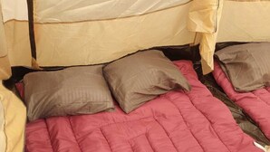 A bed with a red quilt, two pillows, and a beige blanket. - CAMPING CABIN 5 (Bacalar)