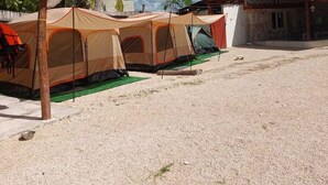 A campsite with tents, a palm tree, and a building with a red roof. - CAMPING CABIN 5 (Bacalar)