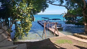 A dock with boats, clear water, and trees. - CAMPING CABIN 5 (Bacalar)
