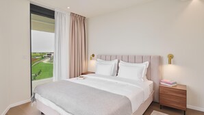 Un dormitorio con una cama grande, una mesita de noche, una lámpara y vistas a un paisaje verde a través de una ventana.