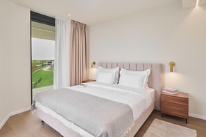 A bedroom with a large bed, a nightstand, a bedside lamp, and a view of a green landscape through a window. - Deluxe Appartment in Crveni Vrh (Umag)