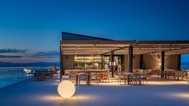 Un espacio al aire libre con mesas, sillas, un bar y vistas al agua.