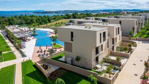 Un hotel moderno con piscina, mobiliario exterior y vista al mar.